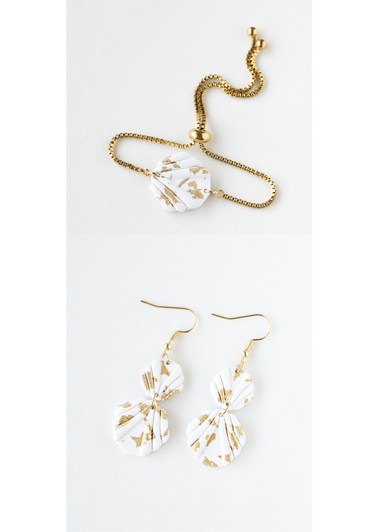 Polymer clay earring and bracelet jewelry set with white and gold leaf accented shell shaped pieces on a white background.