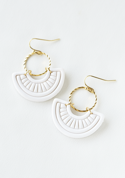 White boho earrings with gold accents on a white background