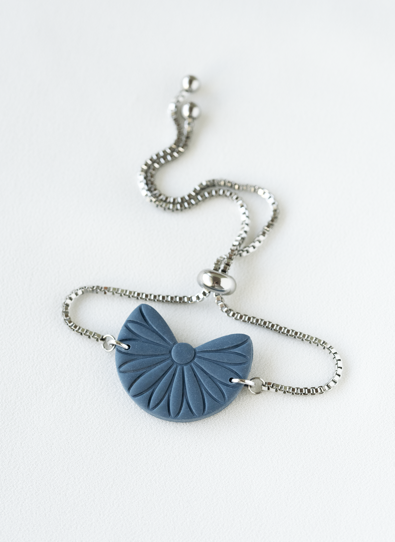 adjustable stainless steel bracelet with a blue boho pendant on a white background