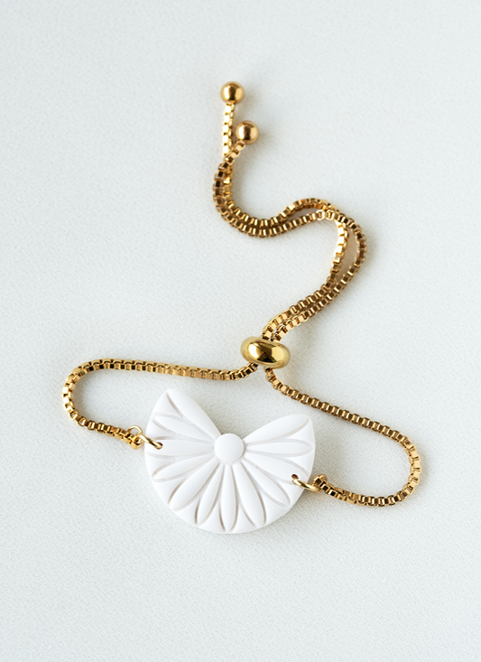 adjustable gold plated stainless steel bracelet with a white boho pendant on a white background