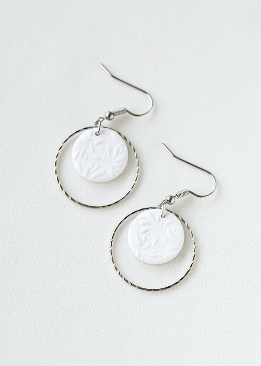 Pair of stainless steel earrings with white polymer clay pendant.