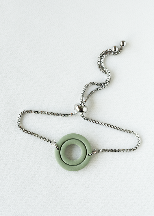 adjustable stainless steel bracelet with a green olymer clay pendant on a white background