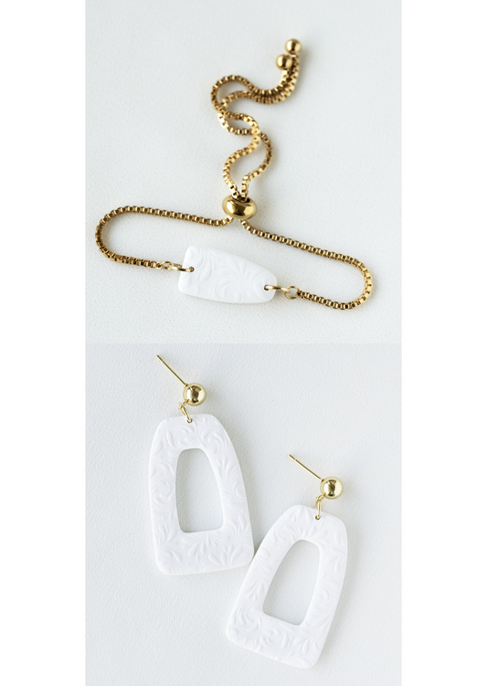 Polymer clay earring and bracelet jewelry set with white pendants on a white background.