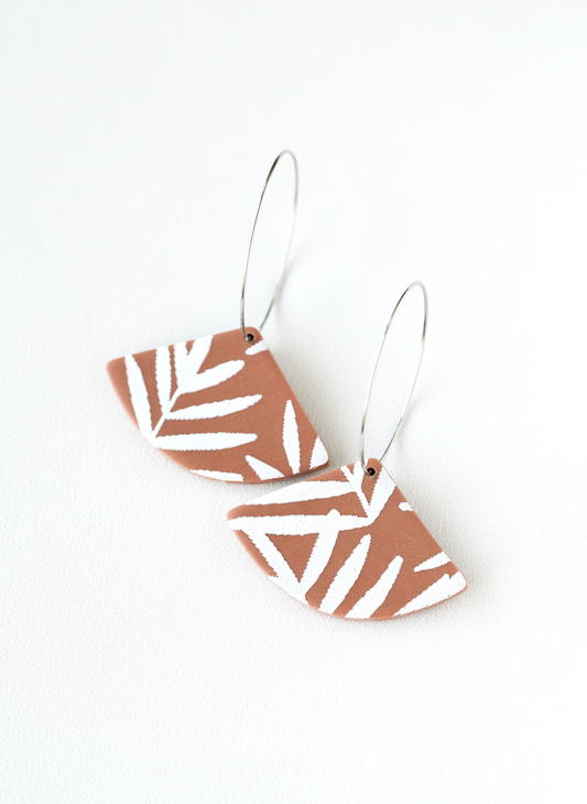 Pair of polymer clay hoop earrings with leaf pattern on a white background